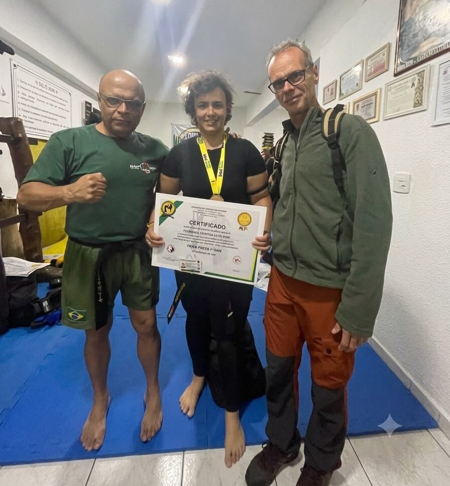 Fernanda Pieri recebe certificado de graduação ao conquistar o 1º Dan de Faixa Preta em Kickboxing e o Preijed Preto no Muay Thai, ao lado do mestre Carlos Oliveira Souza, em Contagem (MG).